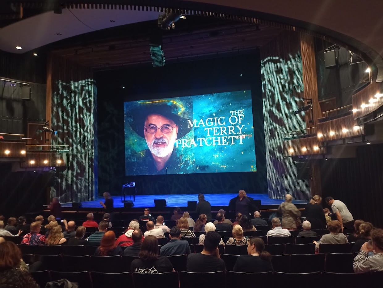 Large screen on the Bloomsbury stage showing the Cover of The Magic of Magic