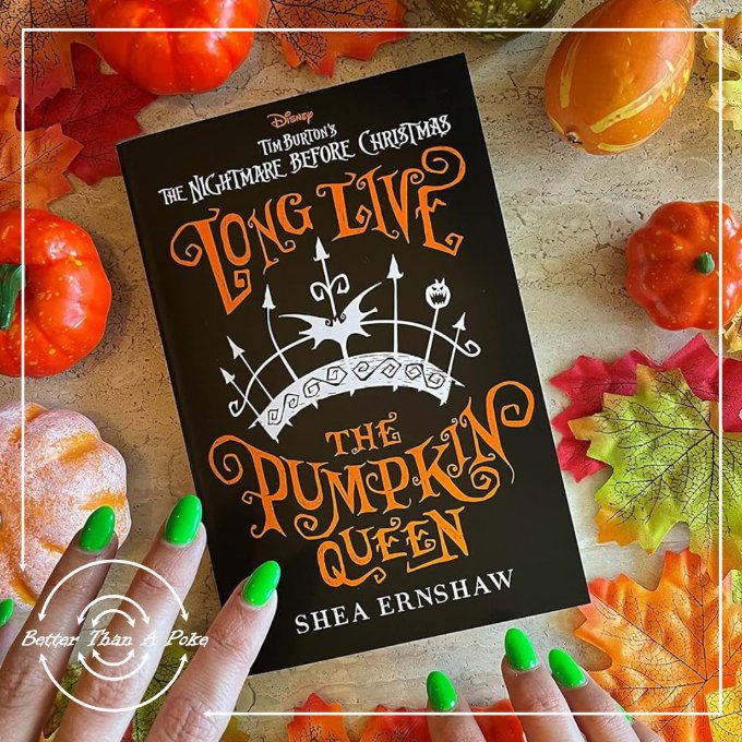Long Live the Pumpkin Queen - Shea Ernshaw A festive table covered in small pumpkins with a pair of hands with green nail polish reaching for a copy of Long Live The Pumpkin Queen by Shea Ernshaw